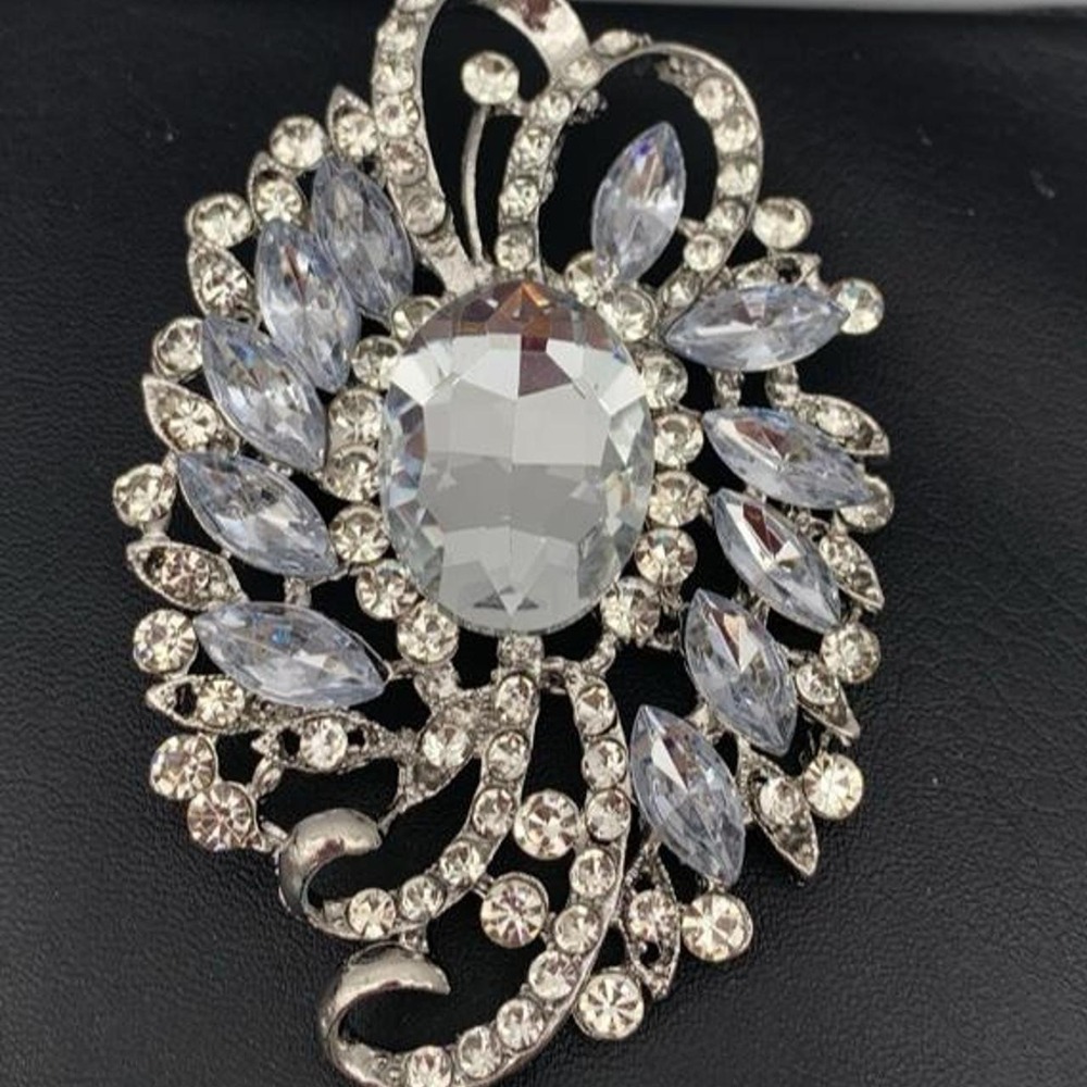 Large silver tone brooch with large central crystal surrounded by rhinestones